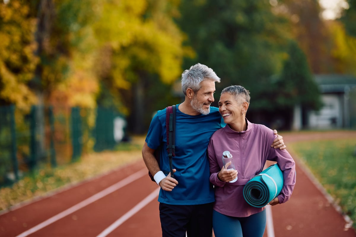 Happy mature sports couple walking on running track while exercising at the park
